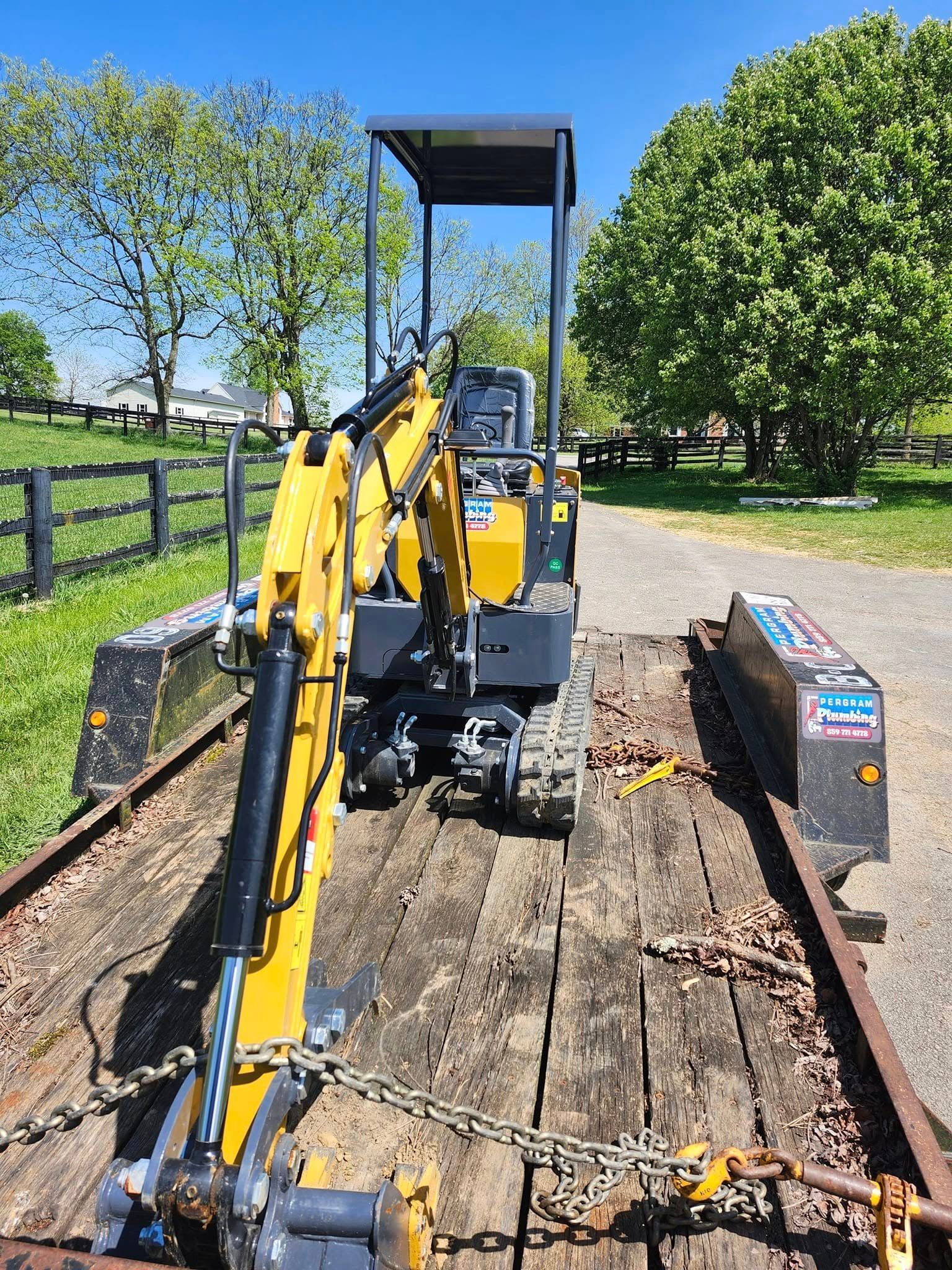 Yellow and black mini excavator on a trailer, ready for transport.