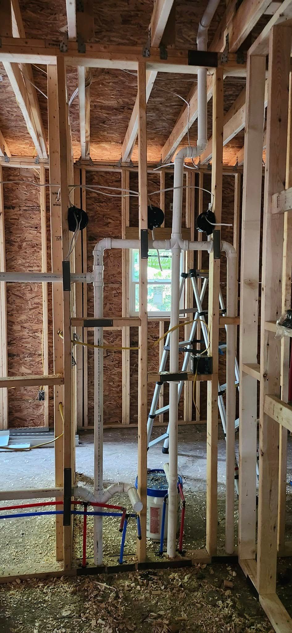 Framed wooden construction with plumbing pipes running through the wall.