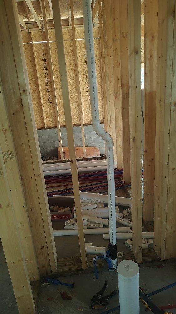 Plumbing pipes installed within the wooden framework of a building's interior during construction.