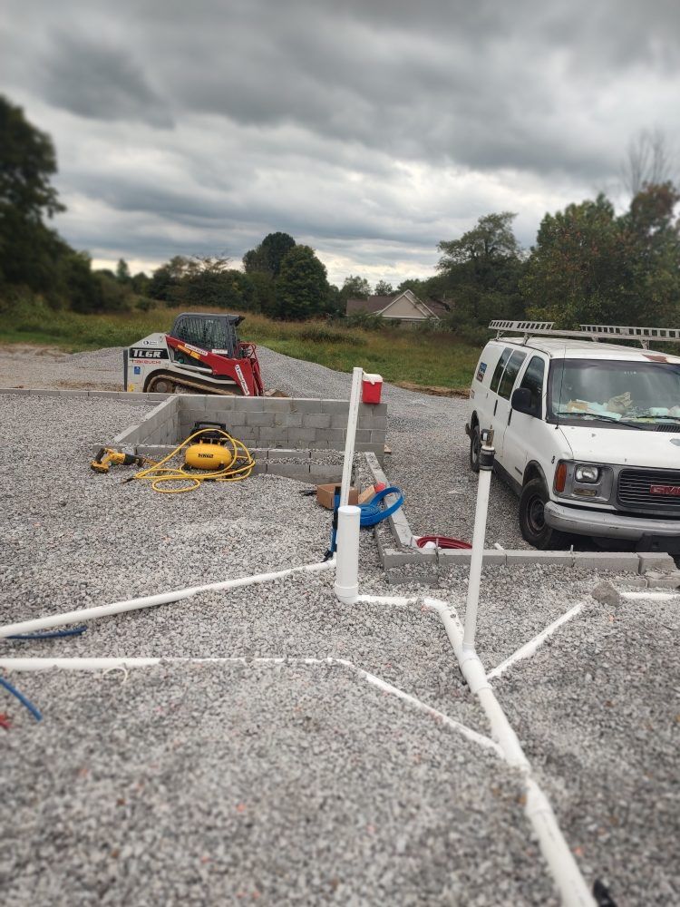 Wooden framing of a room with exposed plumbing. White pipes run up and down the wall. Blue and red pipes along the floor.