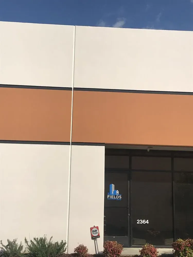 Exterior of a commercial building with white and orange panels, a glass door, and the address 2364.