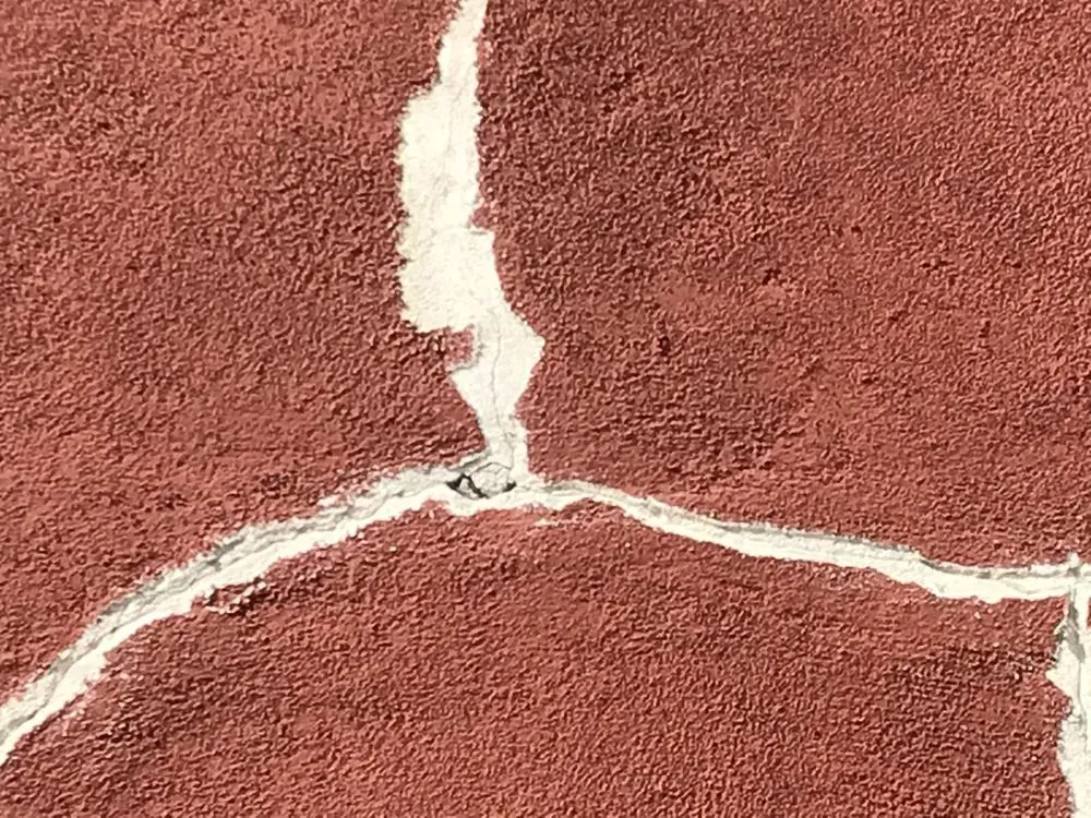 Red textured surface with white, cracked lines.