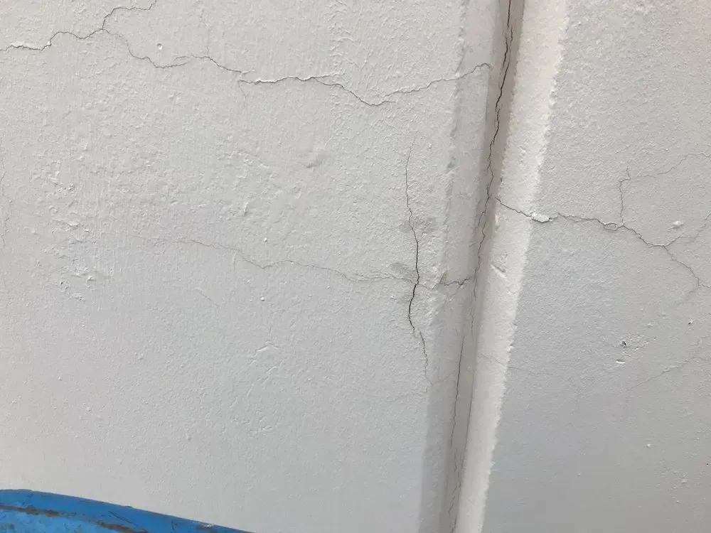 White ceiling with cracks, near a white pipe.
