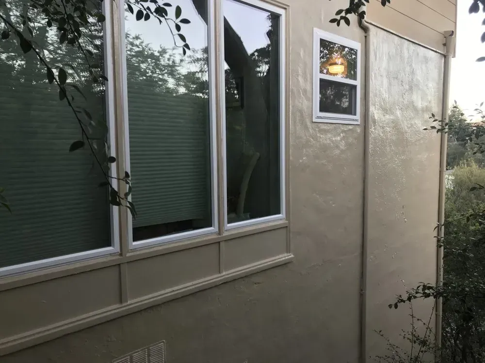 Beige building exterior with windows and surrounding greenery.