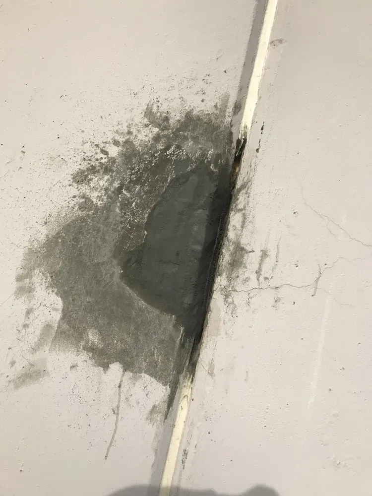 Patch of gray concrete or cement repair on a white surface, next to a thin white line.