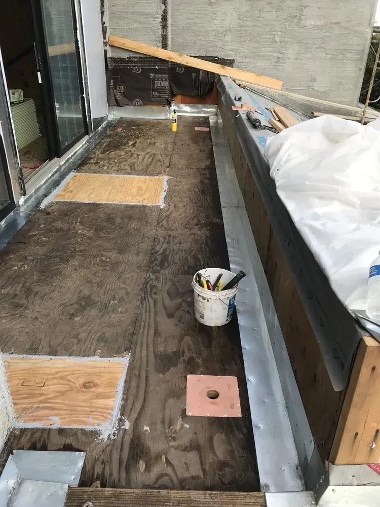Construction of a small outdoor deck with plywood flooring, tools, and materials.