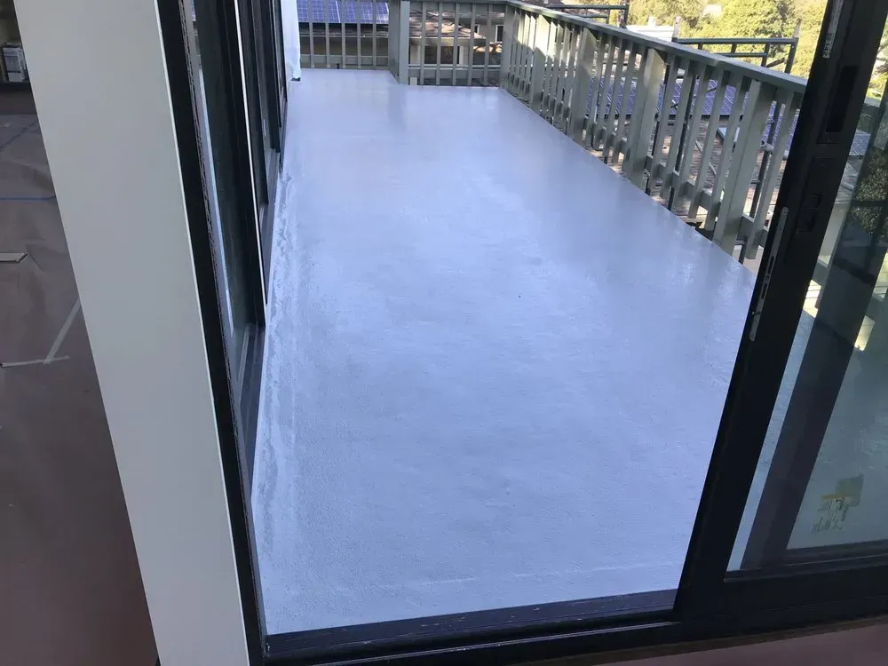 A light gray painted deck with sliding glass door to a wood railing balcony.