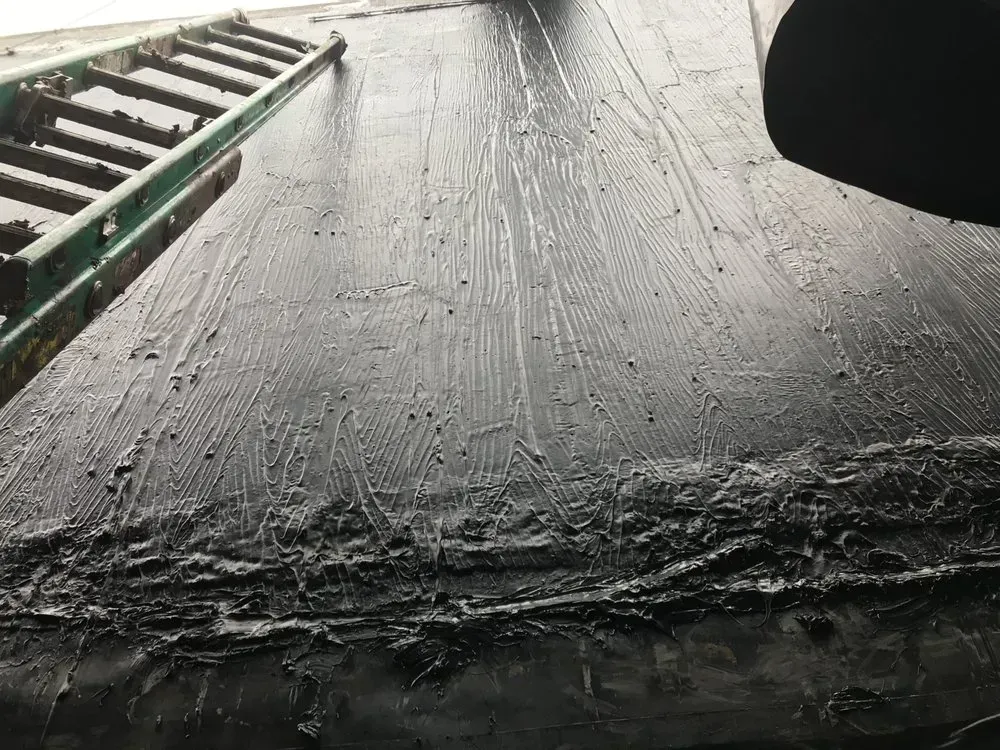 Black tar roof with ladder; close-up showing texture and layering.