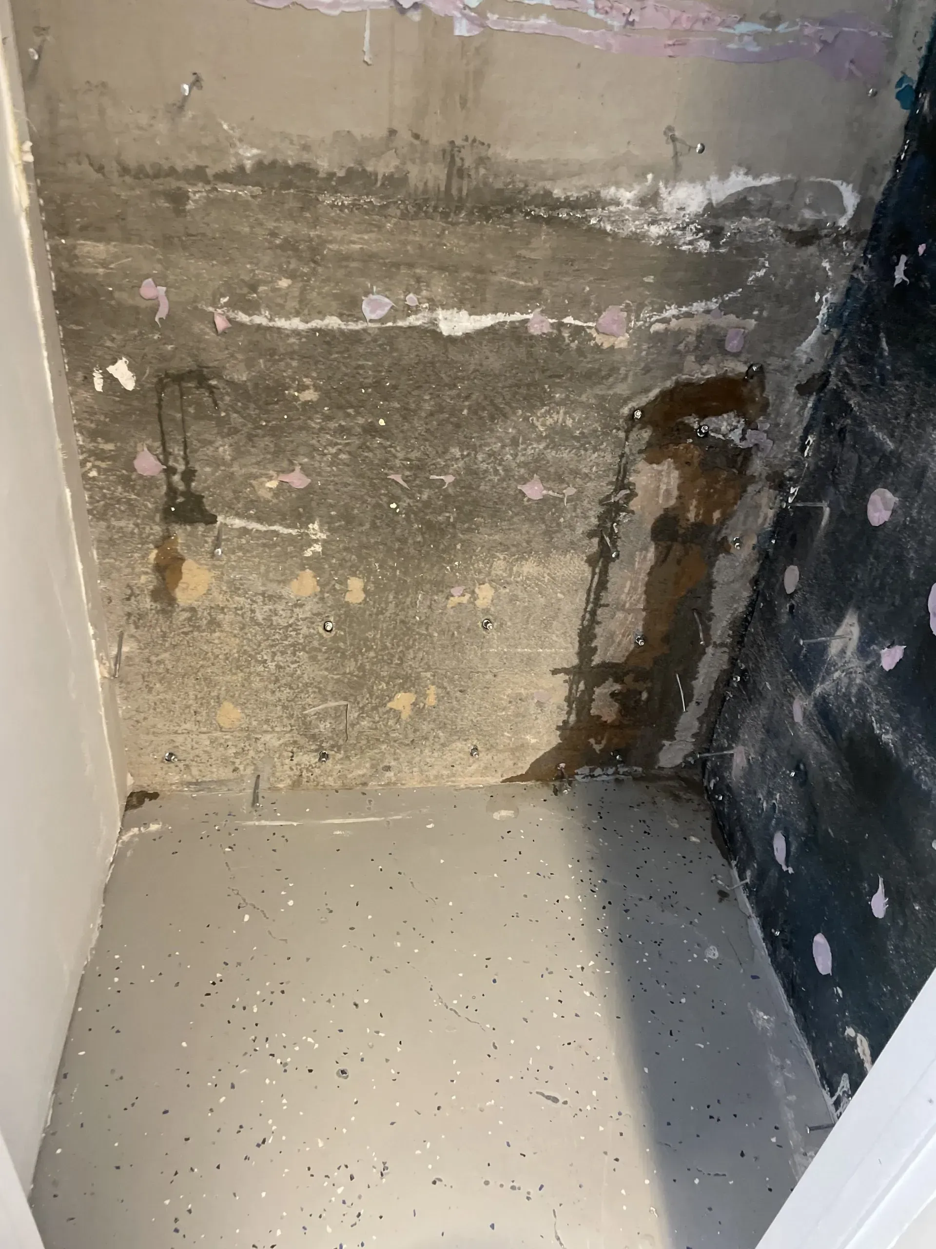 Concrete wall and floor showing water damage and staining; peeling paint.