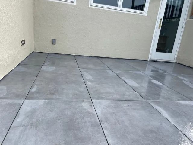 Gray concrete patio with dark lines, against a light beige wall.
