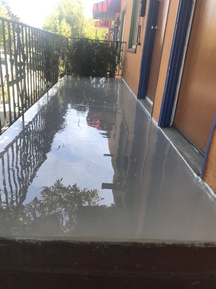Newly poured gray concrete slab on a balcony, reflecting sunlight.