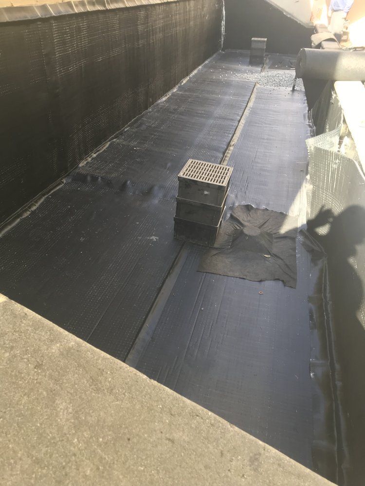 Black tarp lining a concrete rectangular structure. Three grates in the center.