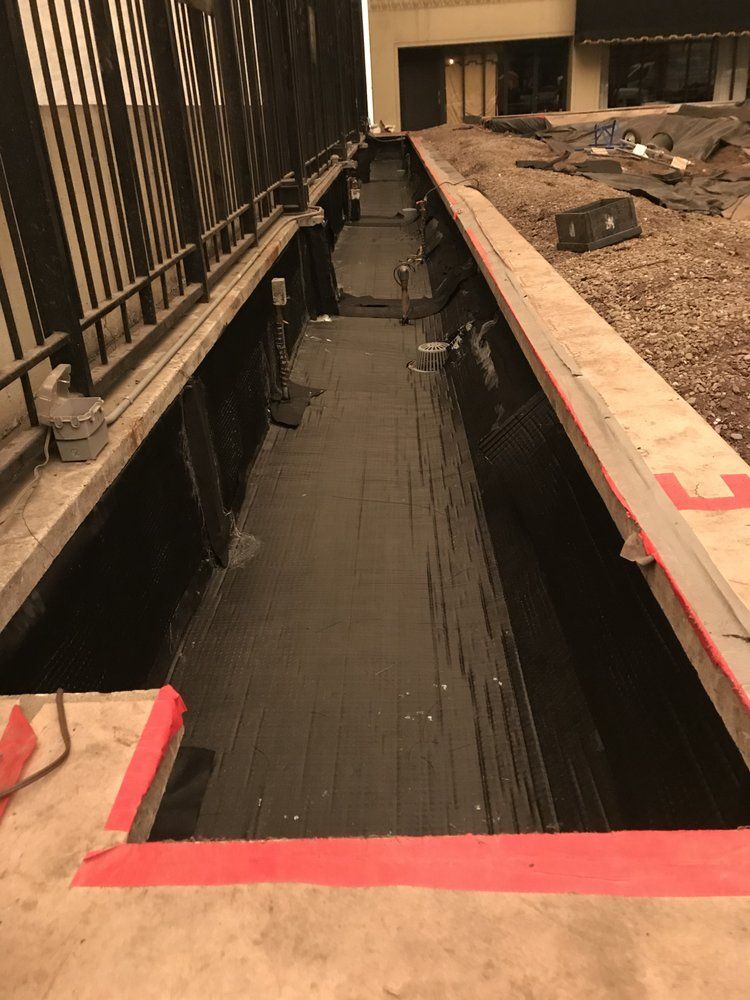 Long narrow trench with black liner; concrete borders with red tape, exterior.