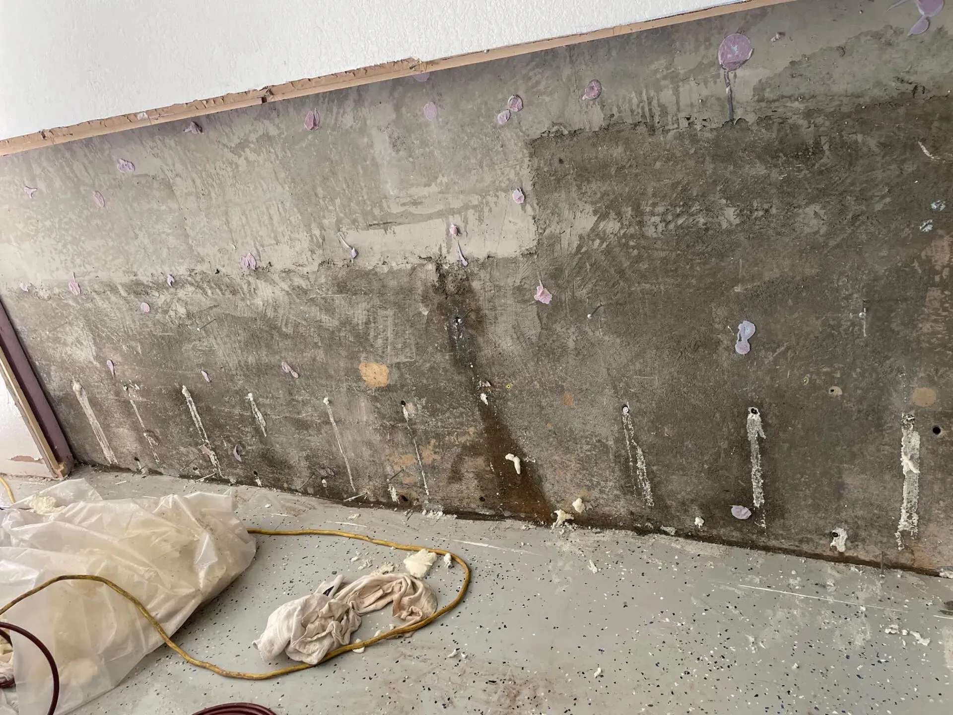 Concrete wall with water damage and peeling paint in a garage.