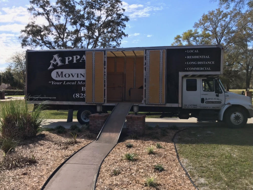 Two delivery men carrying cardboard box - Deep Gap, NC - Appalachian Moving & Storage