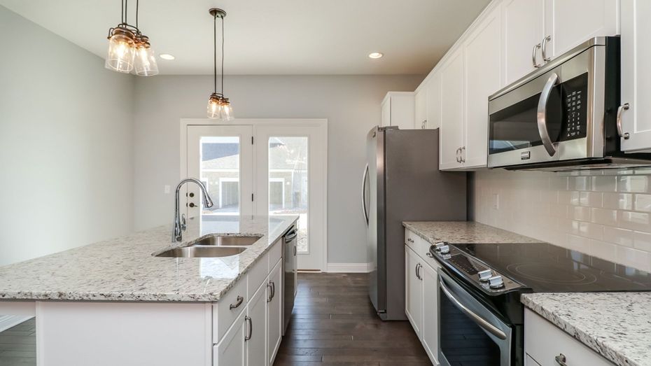 A kitchen with granite counter tops , stainless steel appliances , and a large island.