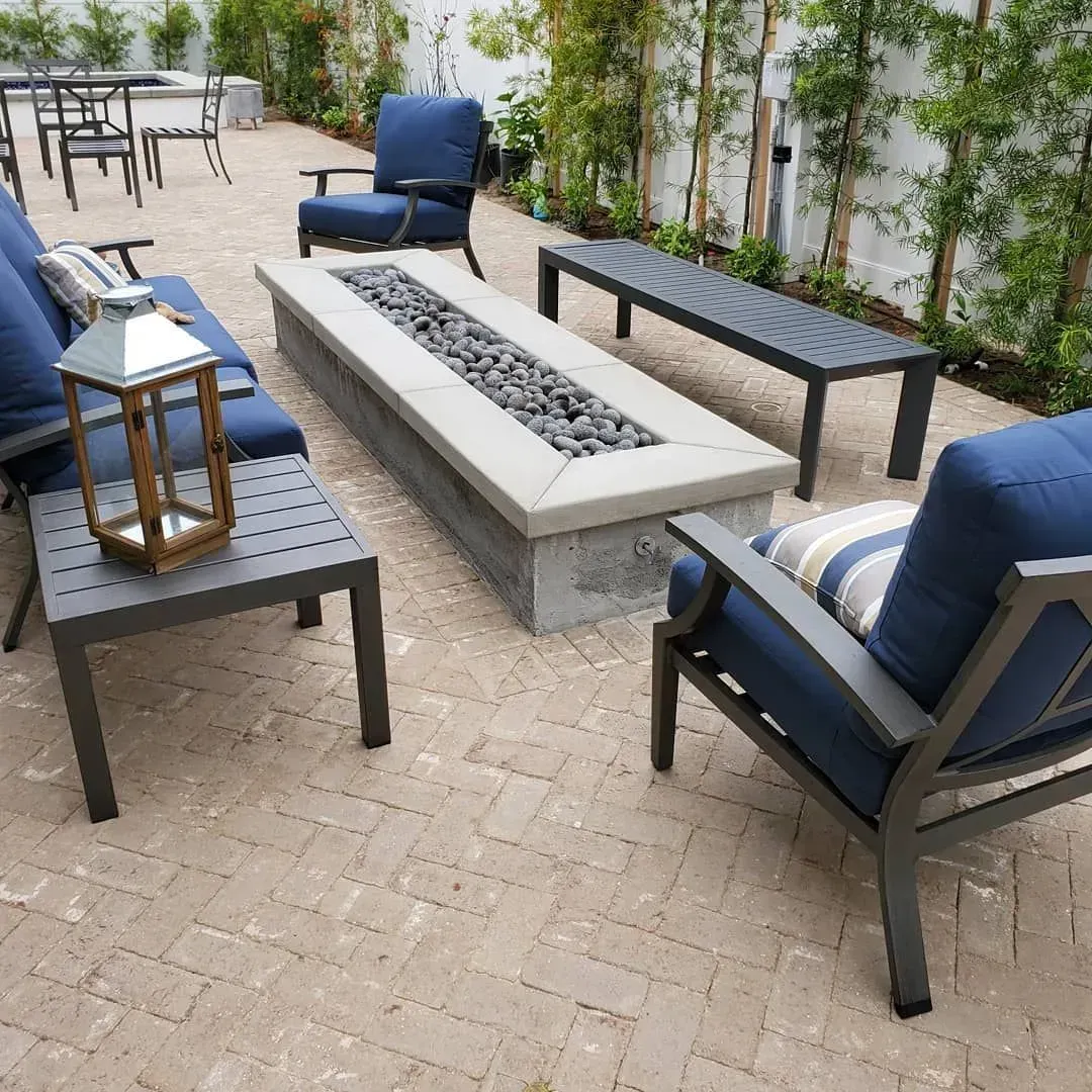 Patio with blue cushioned furniture around a concrete fire pit.