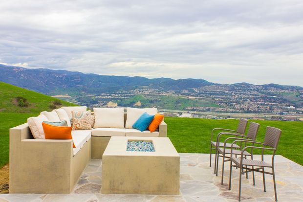 Construction workers pouring concrete on a patio next to a large white house with arches.