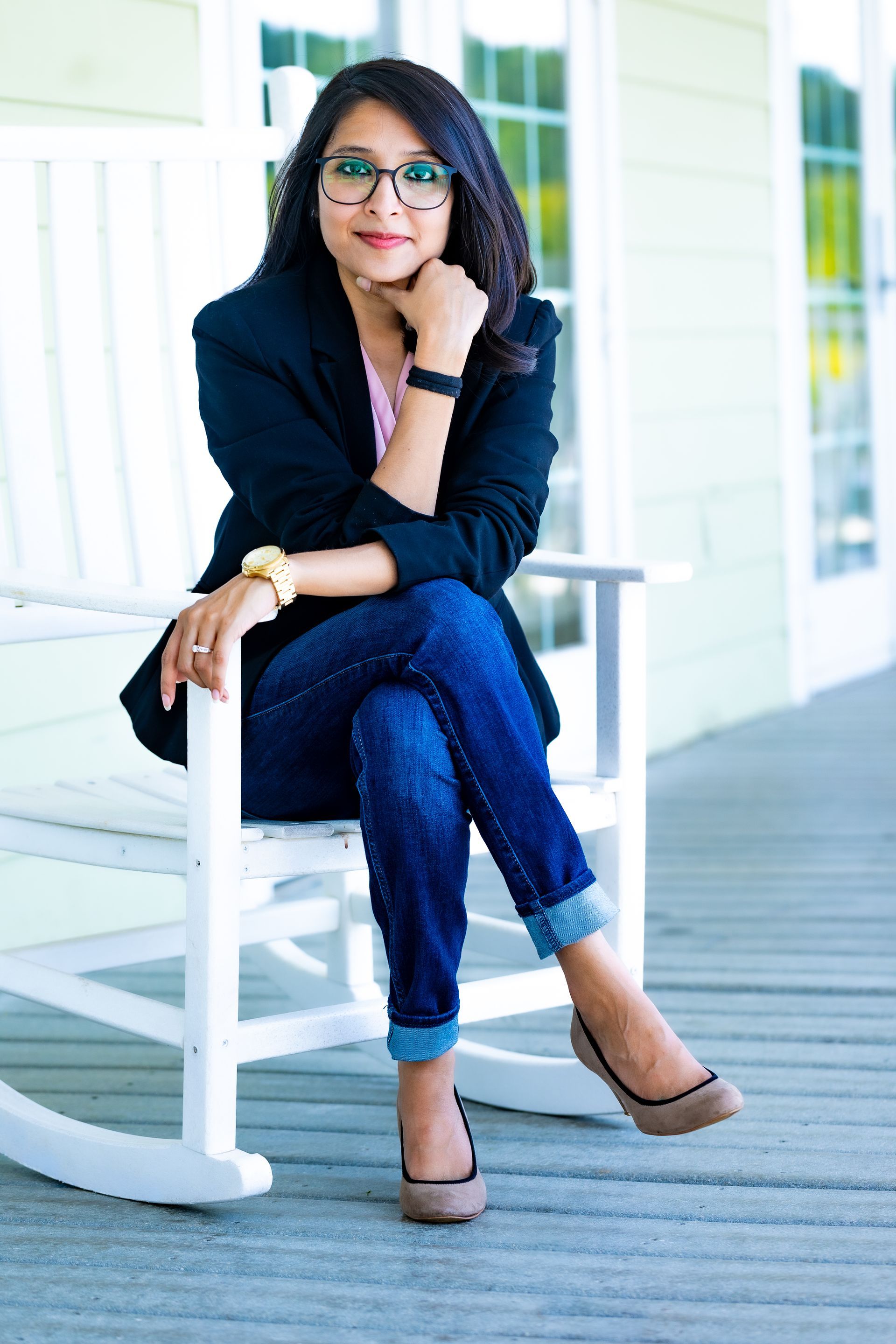 A man is carrying a little girl on his shoulders in front of a brick house.