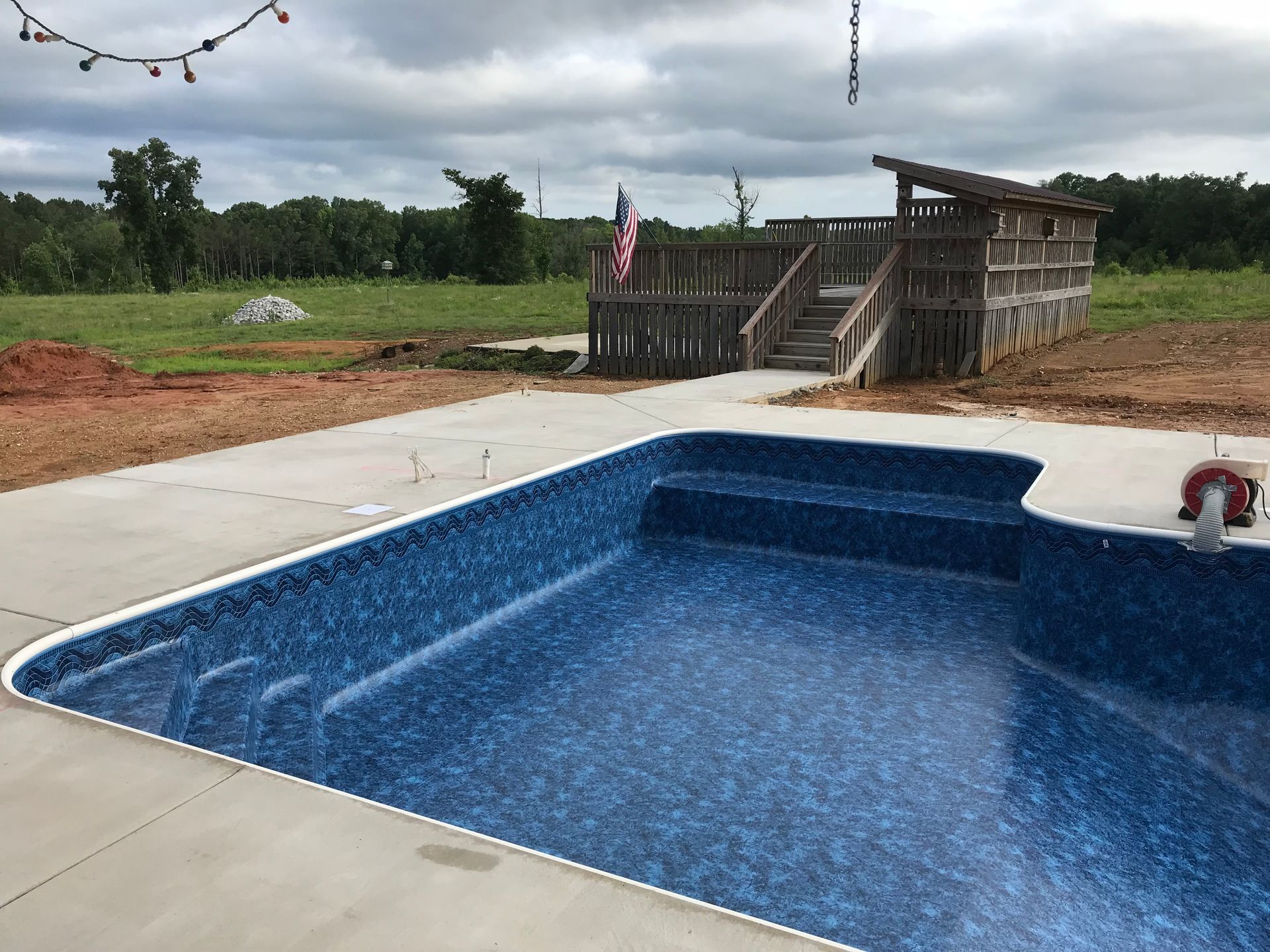 A large swimming pool is sitting on top of a concrete patio.