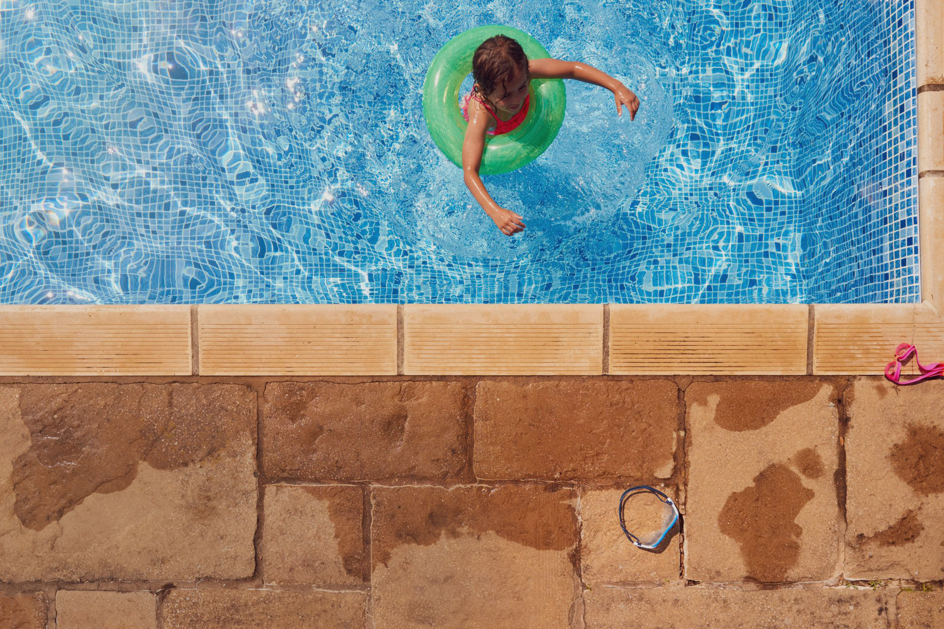 A child is swimming in a swimming pool with an inflatable ring.