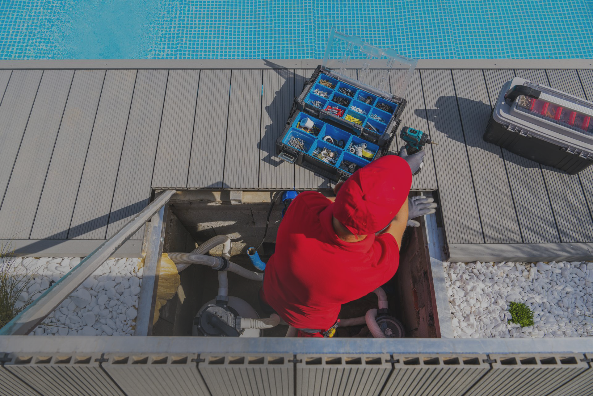 A man in a red shirt is working on a swimming pool.