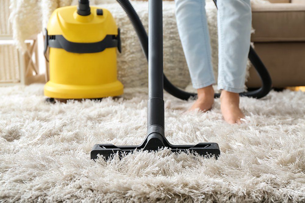 Woman Hoovering Carpet With Vacuum Cleaner
