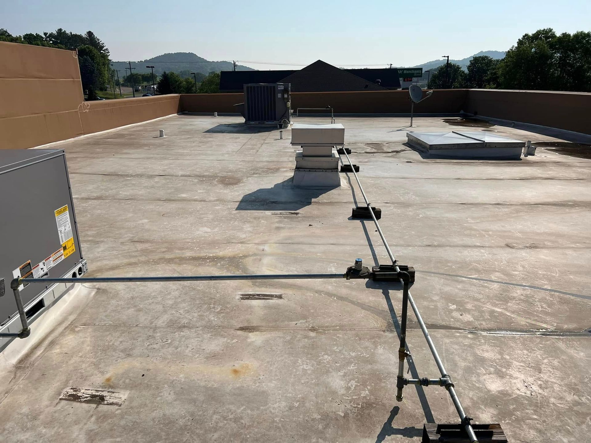 Rooftop with HVAC units, safety railing, and various rooftop equipment under a clear sky.