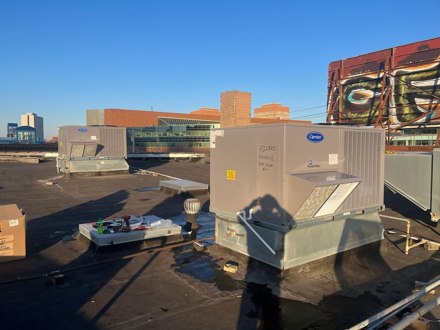 Rooftop scene with HVAC units, cityscape background, and sunny sky.