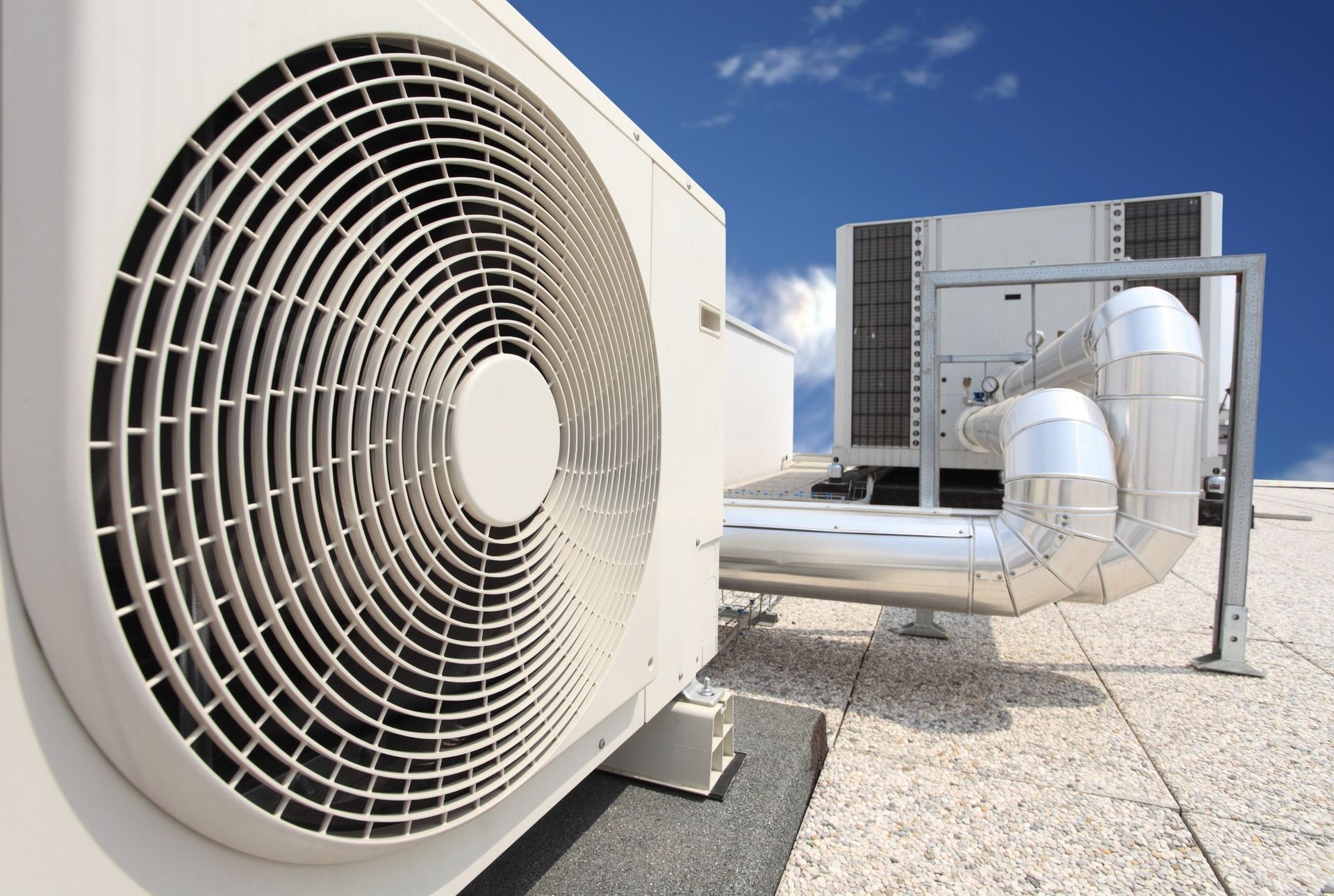 Air conditioning units on a rooftop against a blue sky.