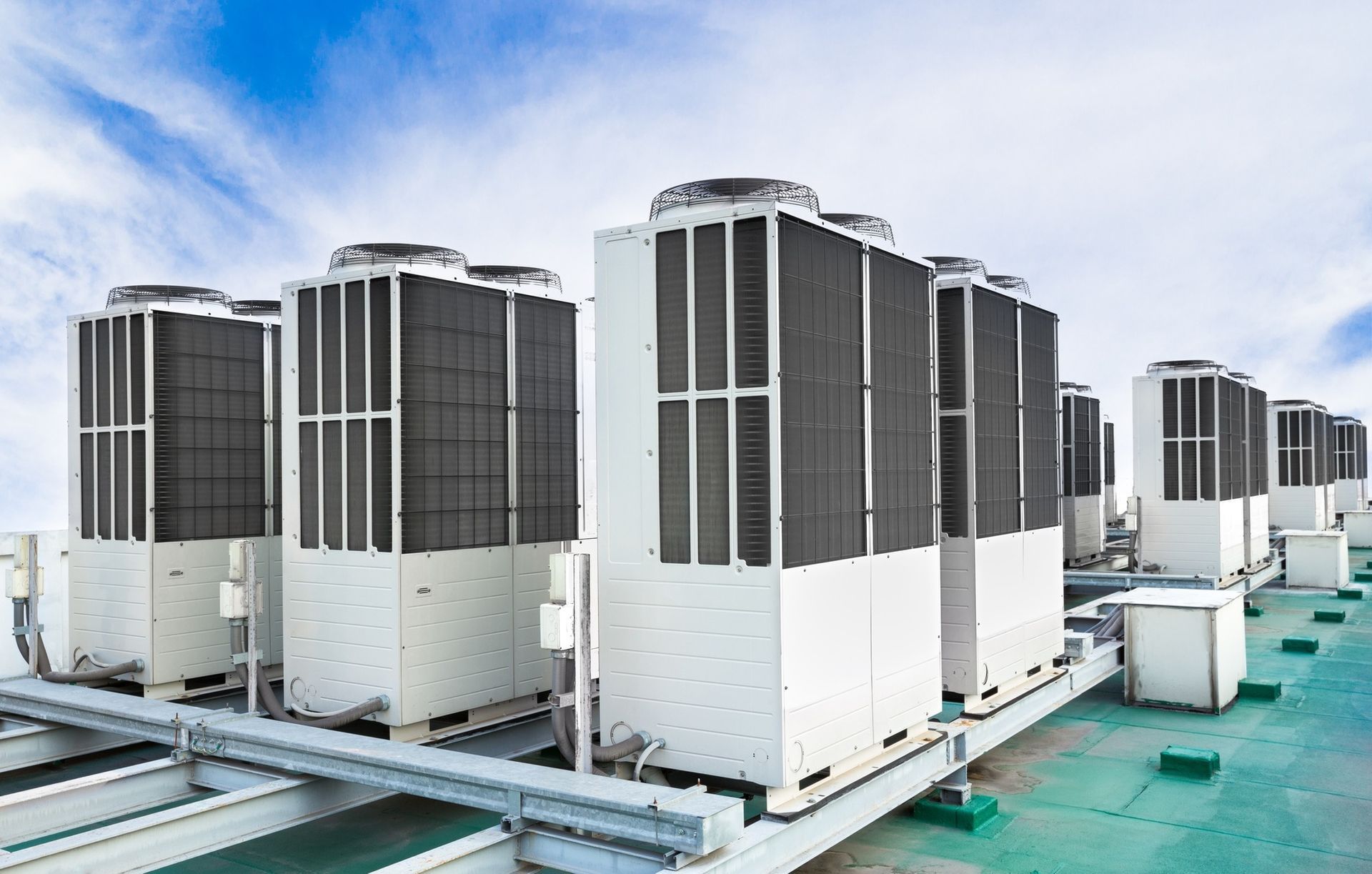 Air conditioning units on a rooftop against a blue sky.