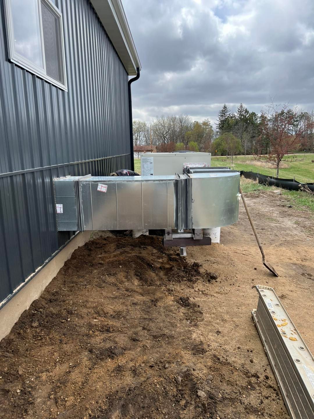 HVAC unit installed on the side of a gray building next to dirt and a construction site.