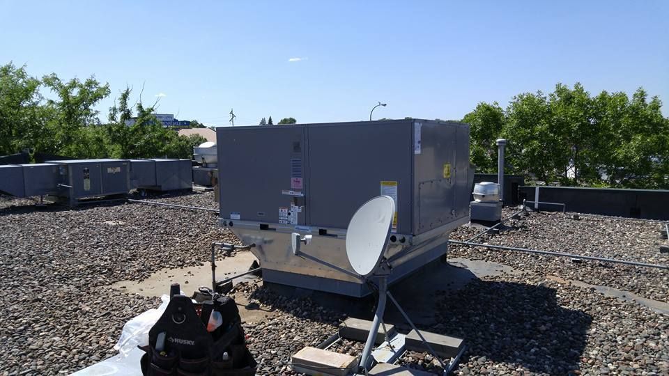 Rooftop with HVAC unit, satellite dish, and work bag. Sunny day.