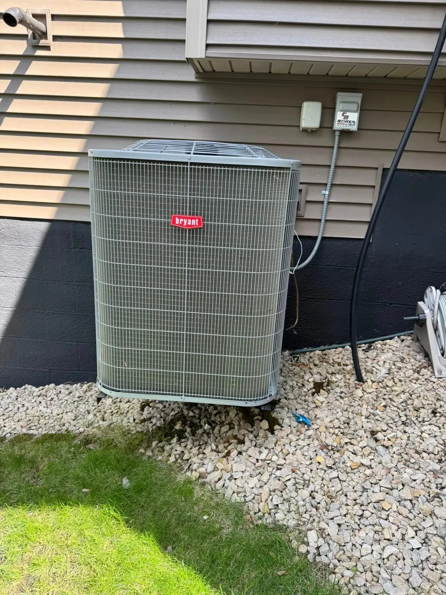 Air conditioning unit outside a building with gravel and grass.