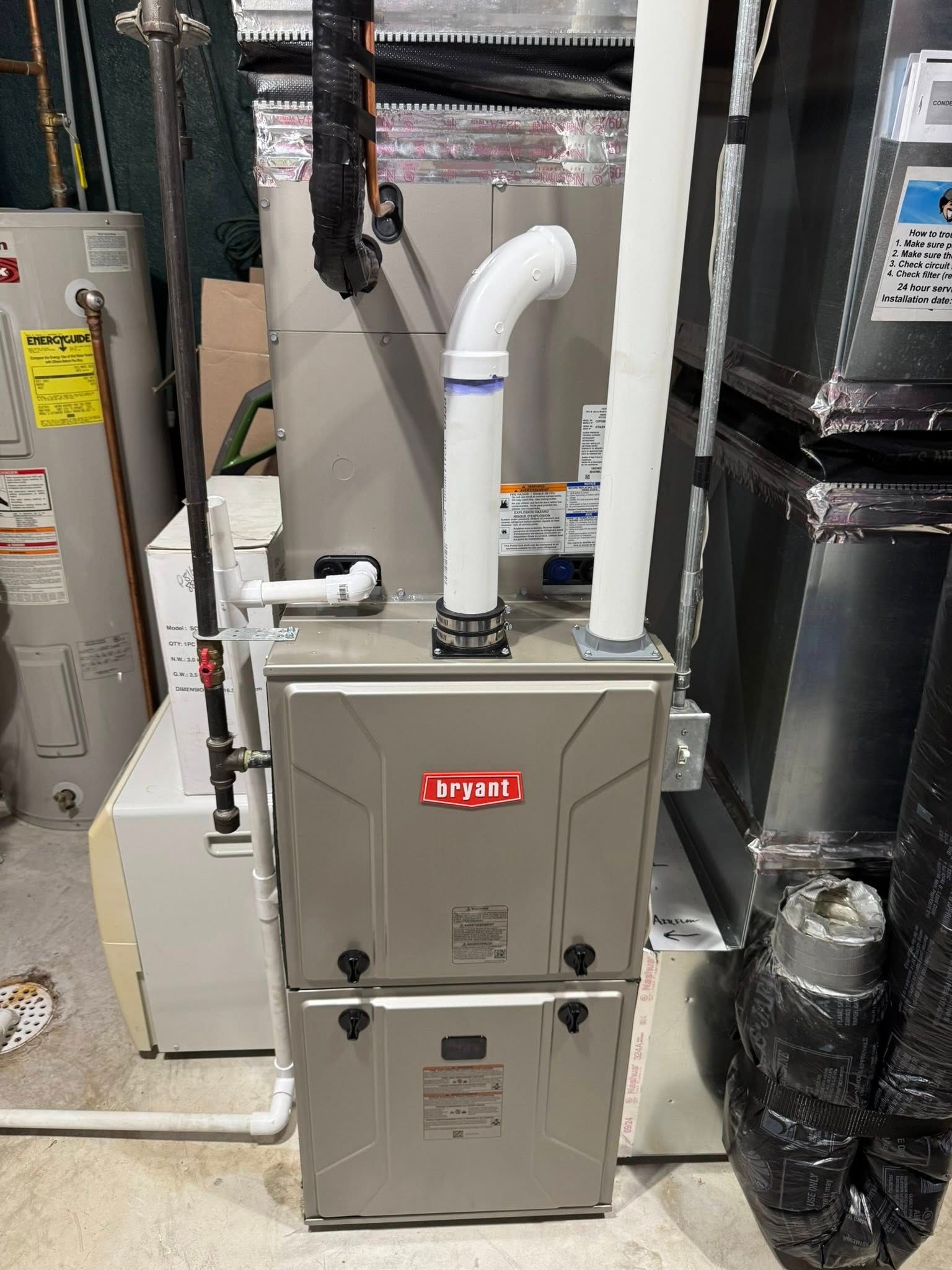 Furnace unit with vent pipes. Gray metal with a water heater on the left.