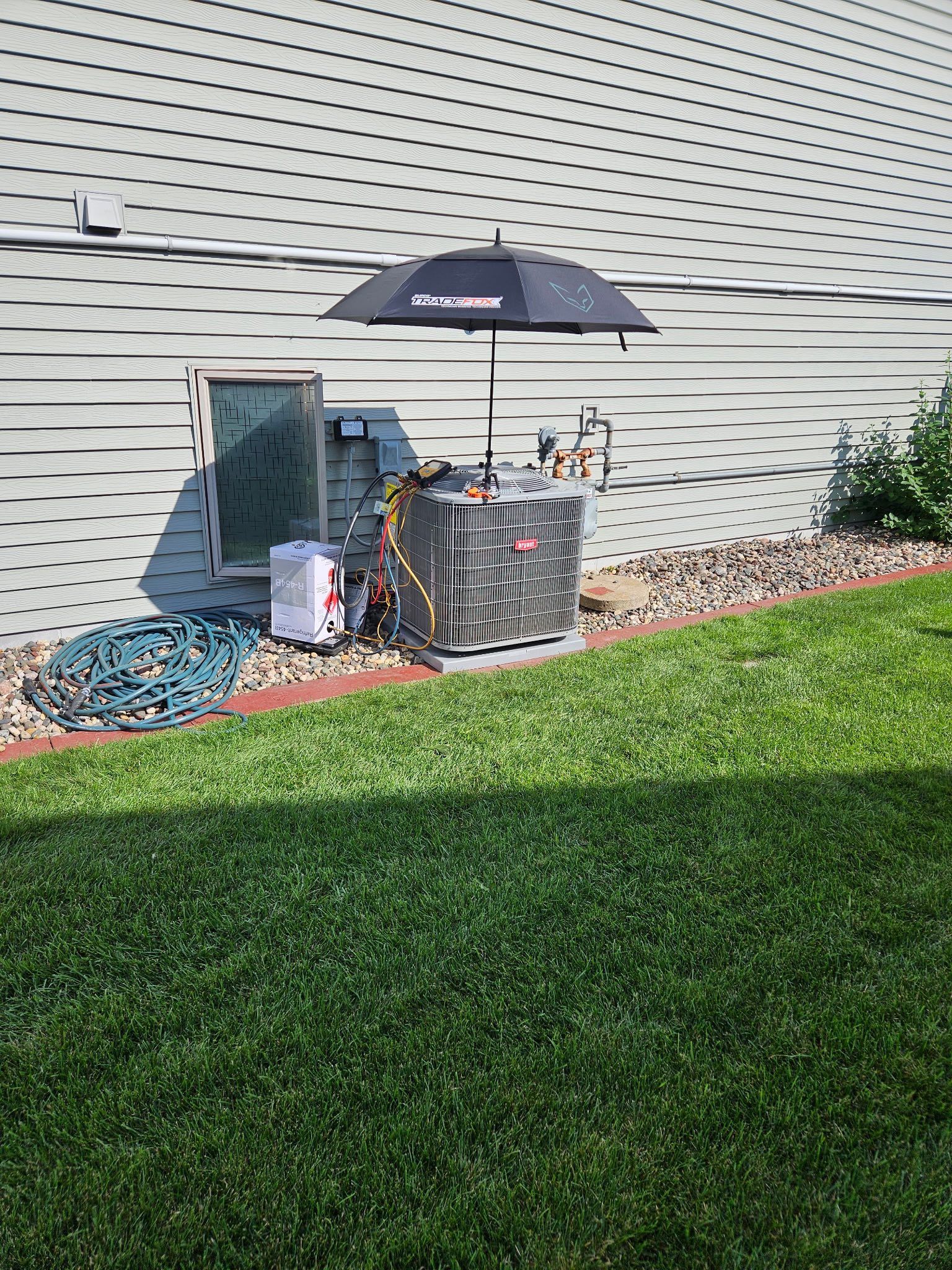 Outdoor electrical equipment, including a transformer, next to a building, protected by an umbrella.