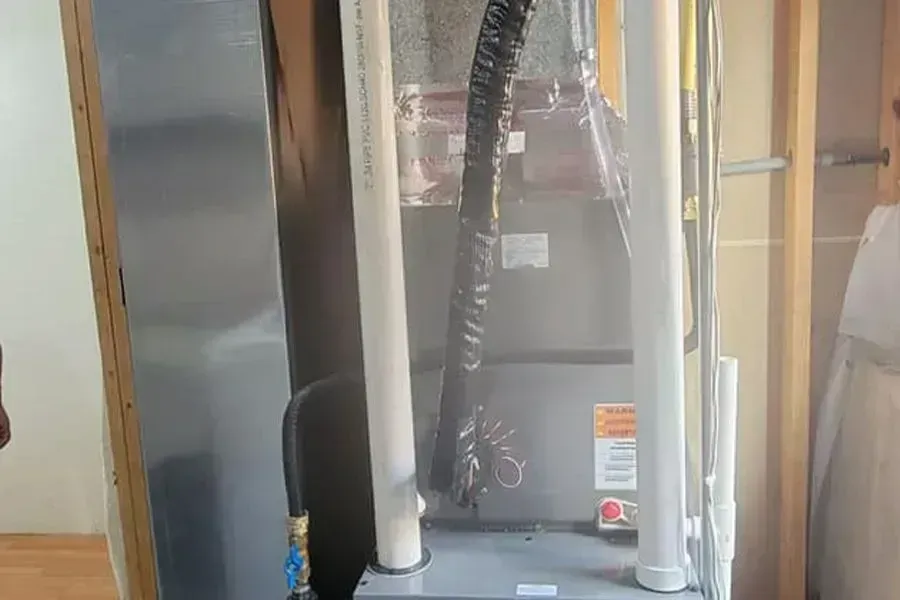 A furnace unit within a wall, with visible pipes and insulation.