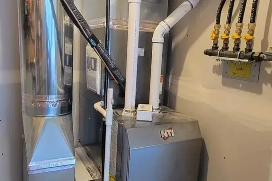 Furnace in a utility room with metal ductwork and gas lines.