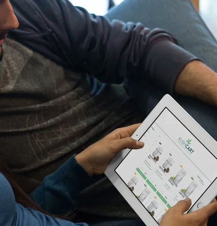 Person using a tablet, browsing a website with product listings; indoors.