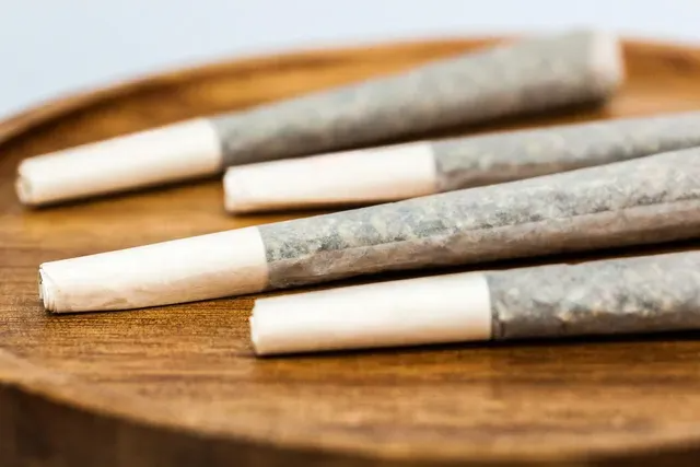 Four marijuana joints on a wooden tray.