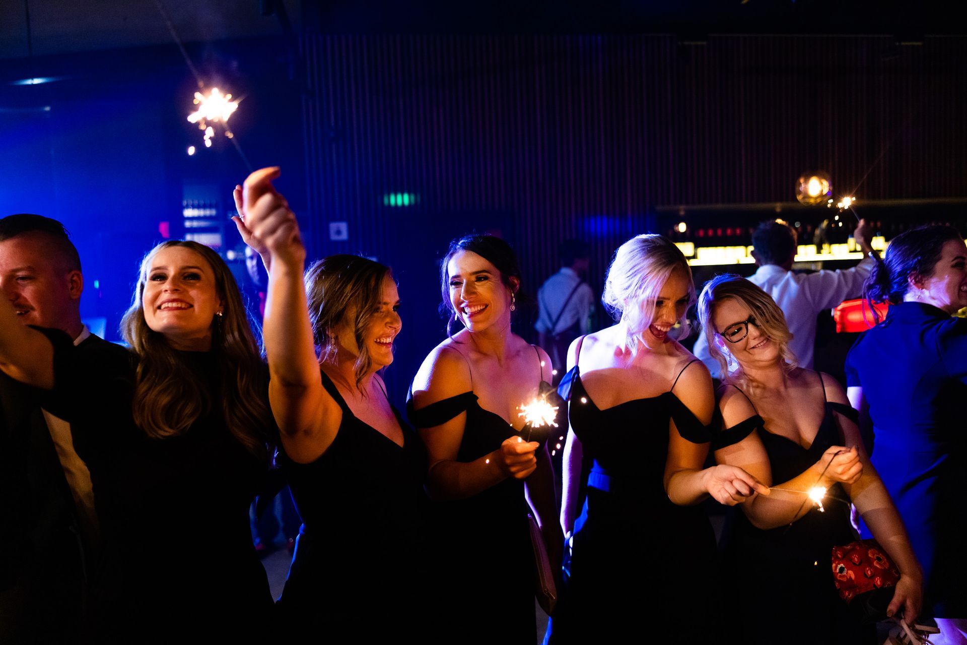 A group of people are holding sparklers in a dark room.