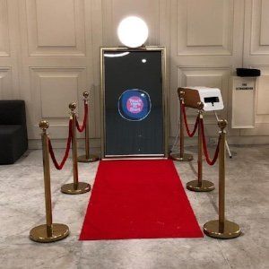 A photo booth with a red carpet and gold poles