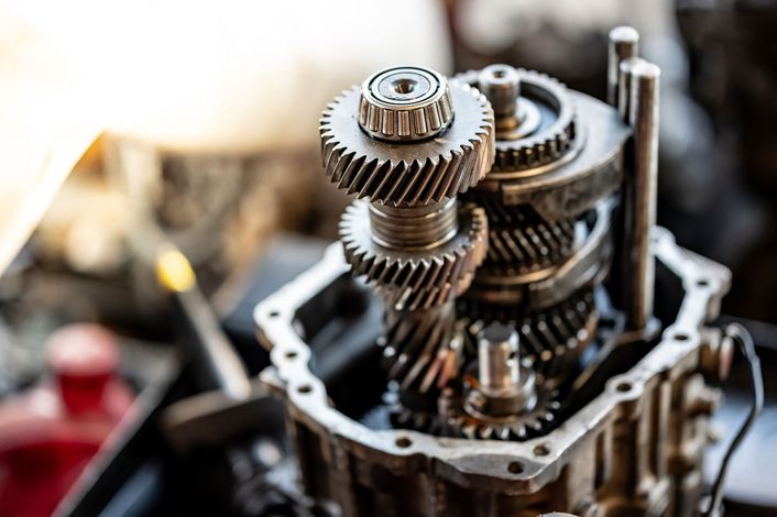 A close up of a gearbox with a screwdriver in the background.