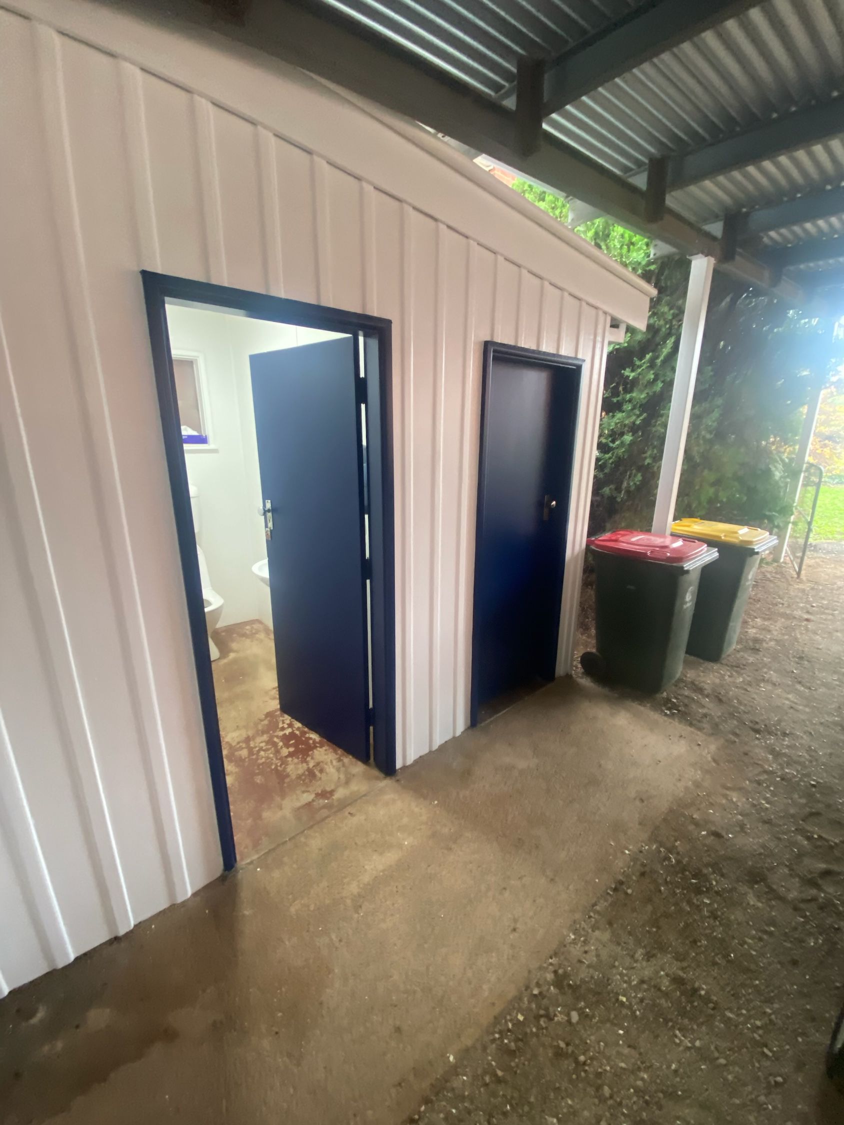 Small White Shed With Two Blue Doors on a Wet Concrete Floor — Robert Seeliger Painter And Decorator in Gilgandra, NSW