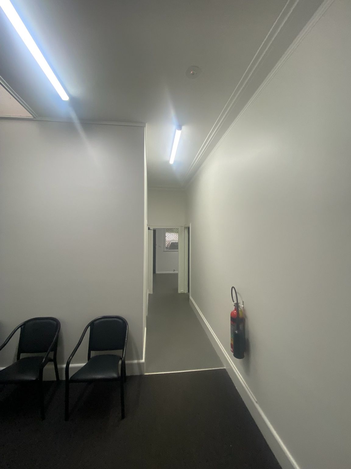Empty White Hallway With Black Chairs on the Left — Robert Seeliger Painter And Decorator in Mudgee, NSW