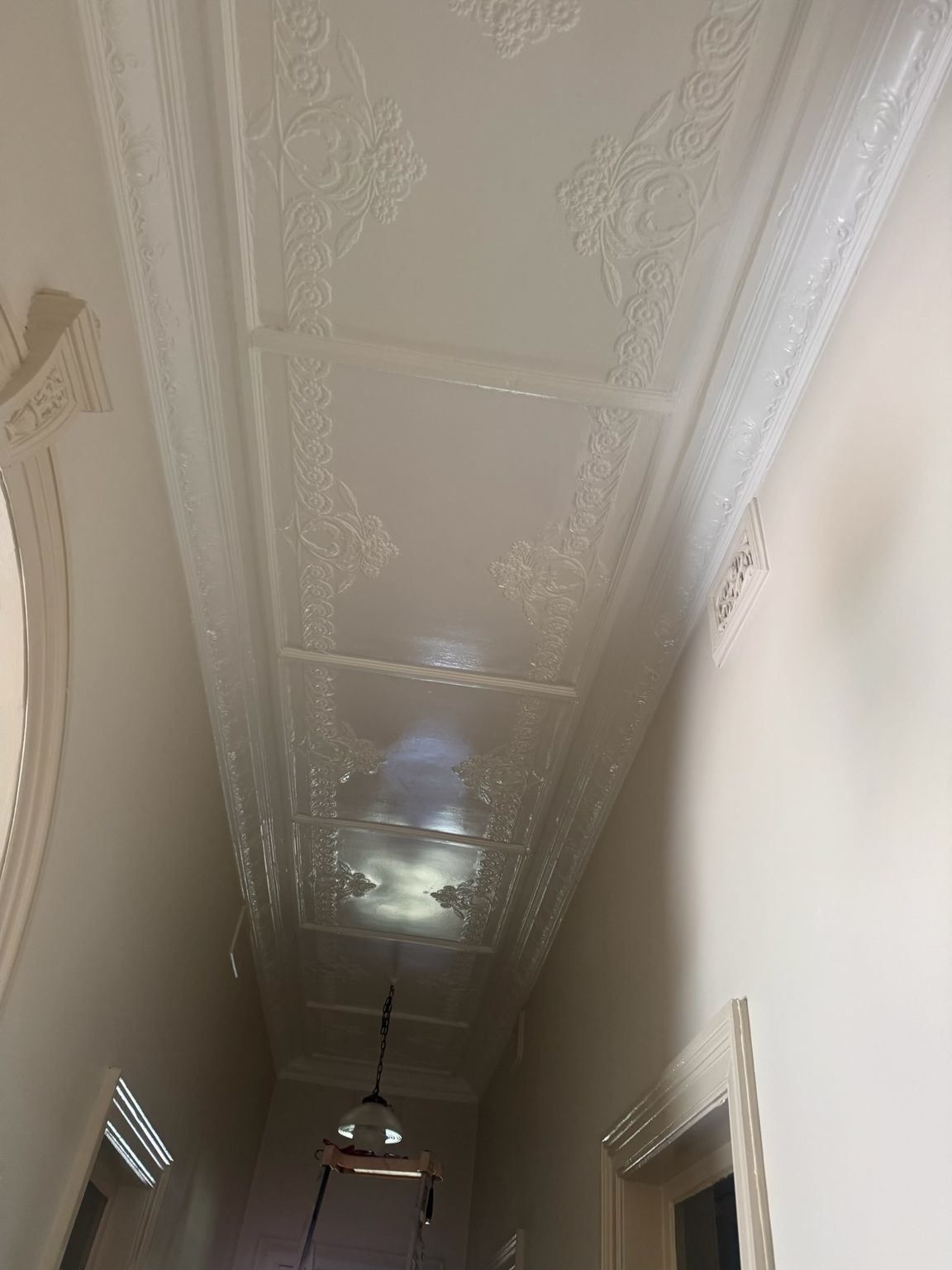 Narrow indoor hallway with ornate white ceiling molding and hanging light fixtures — Robert Seeliger Painter And Decorator in Parkes, NSW