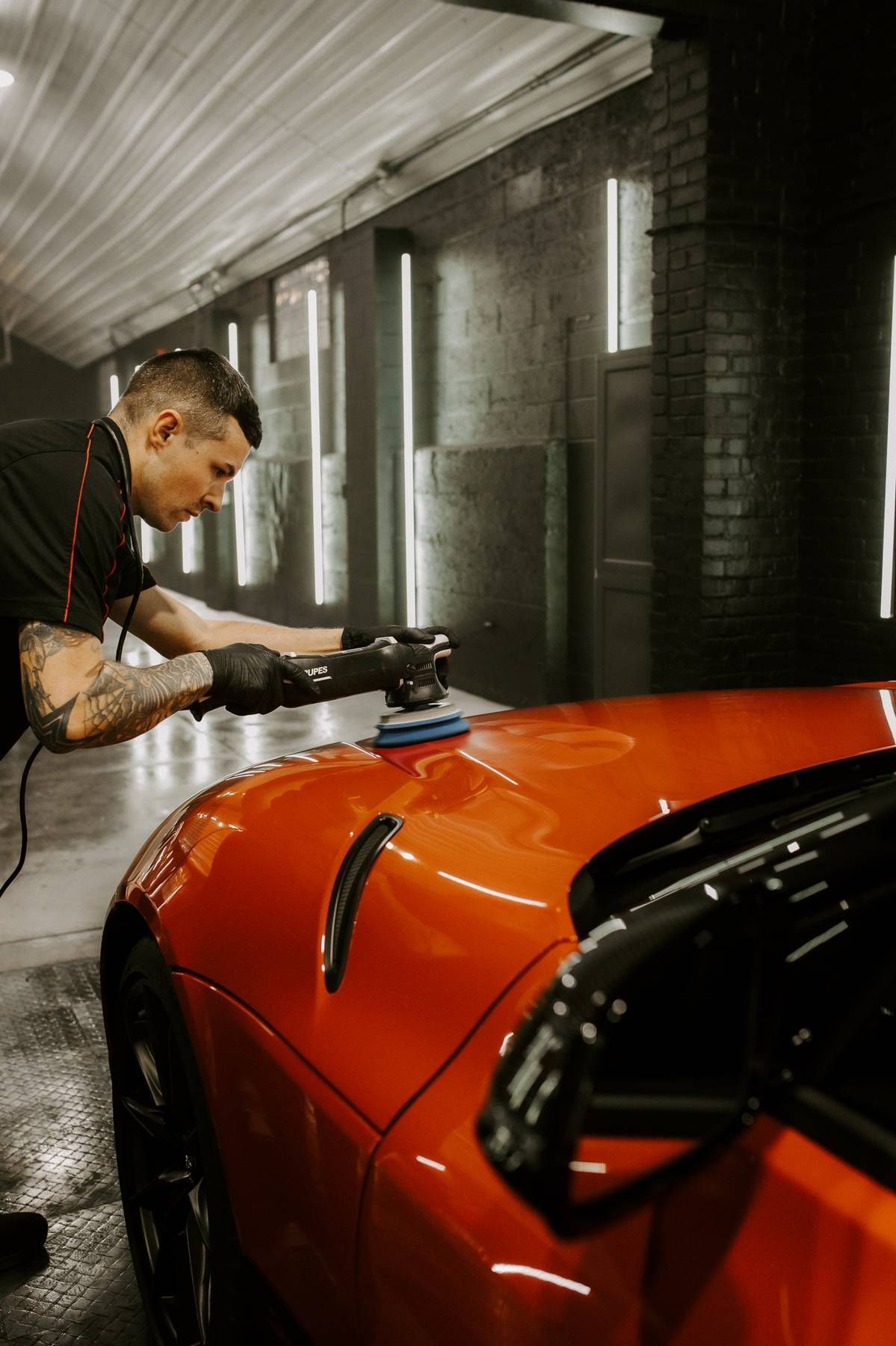 A gold Corvette being washed with a pressure washer inside a garage.