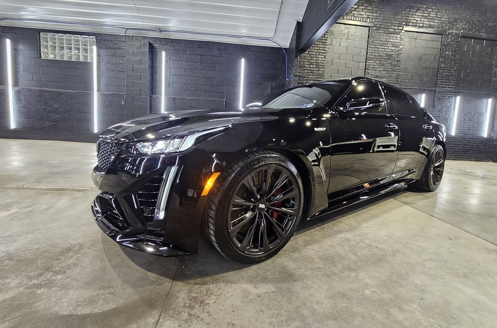 Black Cadillac sports car parked in a garage with bright lighting.