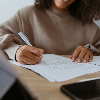 A professional UK CV writer making notes with a biro on paper.