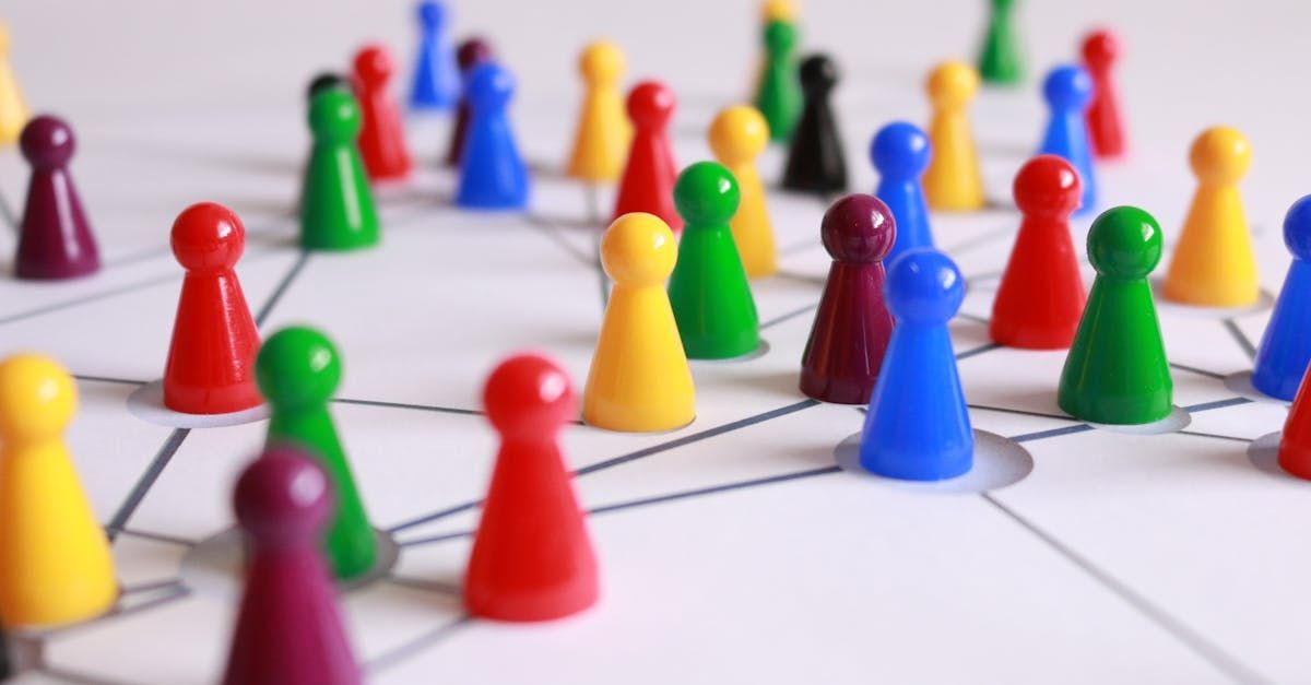 Multicoloured plastic game playing pieces spread out unevenly on a white surface. 